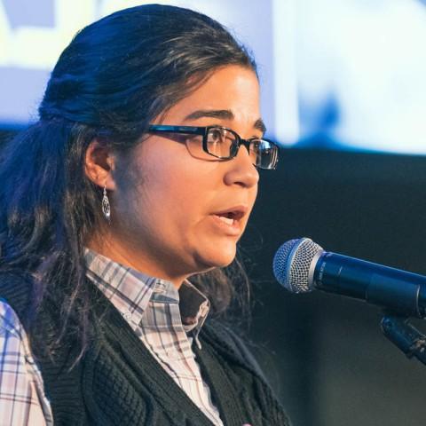 woman on stage speaking into mic